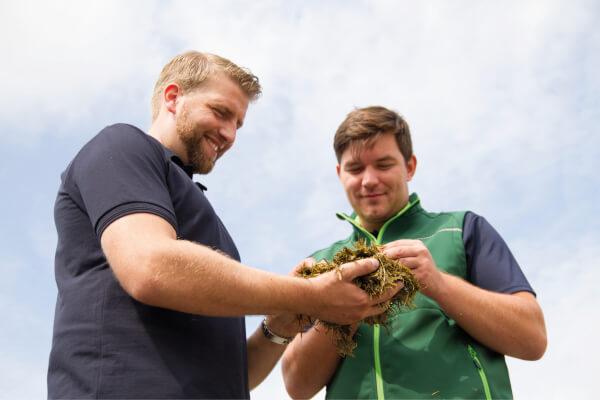 Two men holding silage